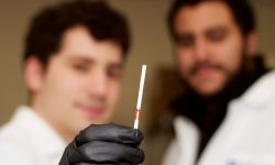 Jonathan Gootenberg y Omar Abudayyeh con una tira de papel de la prueba que muestra un resultado positivo de detección de ADN. Imagen: Laboratorio de Feng Zhang, Instituto Broad, MIT.