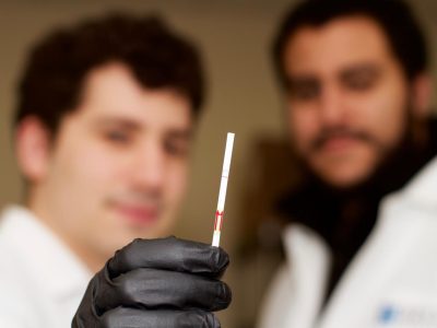 Jonathan Gootenberg y Omar Abudayyeh con una tira de papel de la prueba que muestra un resultado positivo de detección de ADN. Imagen: Laboratorio de Feng Zhang, Instituto Broad, MIT.
